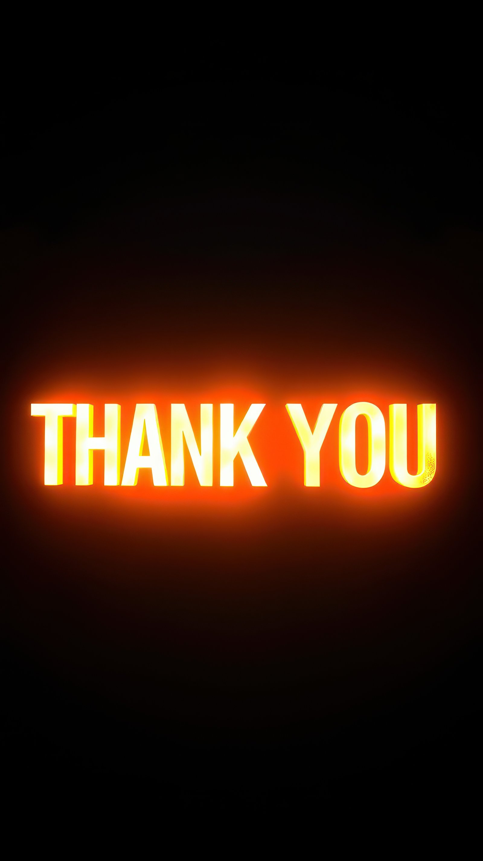 Lighted sign displays a strong message of gratitude in bright orange hue against dark background